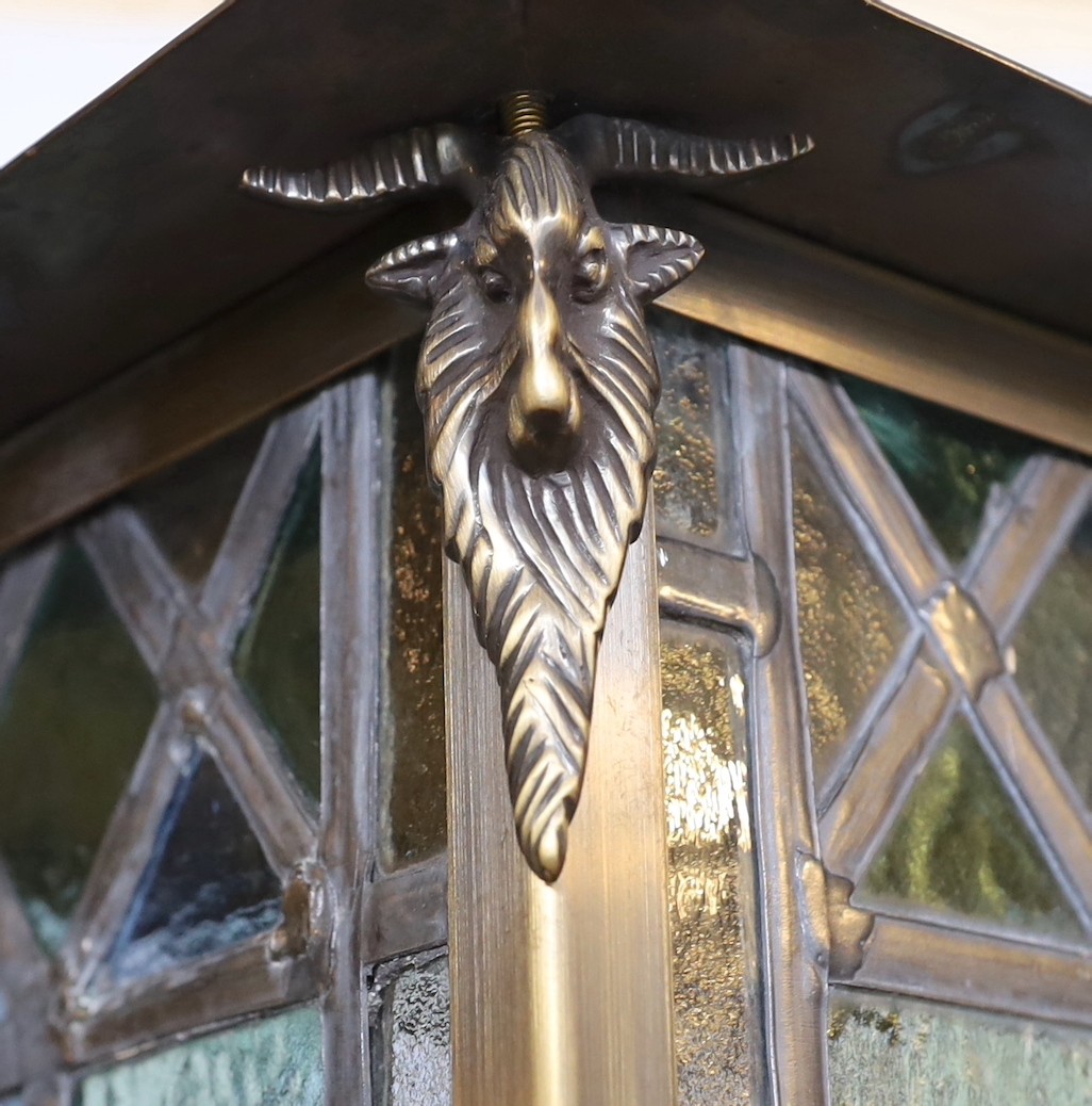 A large Edwardian lacquered brass and leaded glass hall lantern applied with rams head motifs, height 70cm. width 46cm